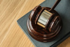 A wooden judge's gavel and sound block rest on a dark hardcover book placed on a light wood surface, reminiscent of courtrooms handling premises liability claims in Washington D.C. The gavel has a polished finish, highlighting the grain of the wood.