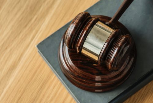A wooden judge's gavel and sound block rest on a dark hardcover book placed on a light wood surface, reminiscent of courtrooms handling premises liability claims in Washington D.C. The gavel has a polished finish, highlighting the grain of the wood.