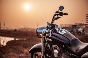 A shiny, black motorcycle is parked outdoors during sunset, its chrome details gleaming under the warm glow. In the background of this Washington D.C. scene, construction equipment stands silhouetted against the orange sky—a reminder of what you should know about safety near busy sites.