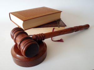 A wooden gavel rests on its block in the foreground, with three stacked legal books focused on boating safety in the background, placed on a white surface.