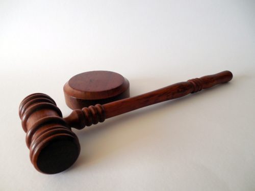 A wooden gavel and a circular sound block rest on a white surface, symbolizing the pursuit of justice. Whether in Washington D.C. or elsewhere, the imagery evokes the solemnity of legal action, like deciding to sue a surgeon for malpractice.