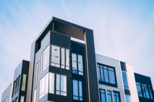 Modern apartment building with large windows under a clear blue sky in Washington D.C. The exterior features a mix of dark and light-colored panels, showcasing contemporary architectural design while prioritizing apartment safety for all residents.