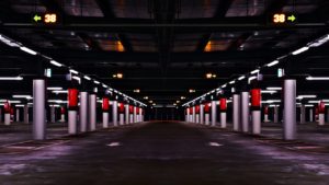 A dark, empty underground parking garage with illuminated signs displaying the number 38 and arrows pointing left and right. The scene is symmetrical, with white pillars and red accents on the walls. The poor lighting could pose a hazard, possibly leading to legal action if someone gets injured.