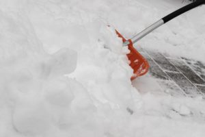 A red snow shovel diligently clears a path through the deep, white snow in D.C., its black and silver handle contrasting with the wintery blanket. Careful movement is essential to avoid any snow & ice accident amidst this serene yet potentially treacherous landscape.