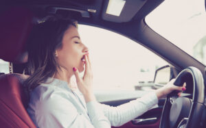 woman yawning behind wheel driver fatigue fatigued driving
