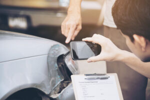 insurance adjuster car accident man taking picture of damaged car