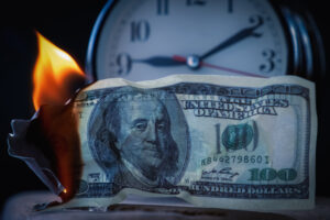 money burning in front of a clock