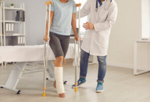 patient with injured leg and crutch working with doctor