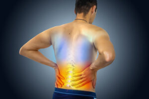 A person shown from behind holds their lower back in pain. The spine is highlighted, with colored gradients from blue to red, illustrating discomfort or inflammation—potentially related to chronic pain compensation issues in Washington D.C.